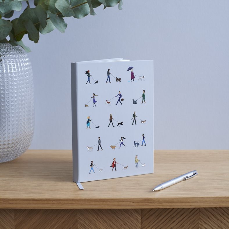 Dog Walker's Notebook standing upright on wooden surface — pale grey illustrated hardback A5 notebook, perfect gift for dog walkers by Sweet William Designs