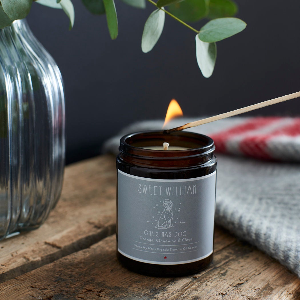 Christmas Dog soy wax candle being lit with a match — orange, cinnamon and clove scented, vegan dog lover gift by Sweet William Designs