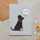 Black Labrador new job congratulations card by Sweet William Designs, featuring an illustrated Black Labrador wearing a bowler hat and red collar, with “Congratulations on your new job!” message and kraft envelope