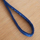 Soft navy velvet handle of the dog lead resting on a wooden table, with the fabric texture in focus
