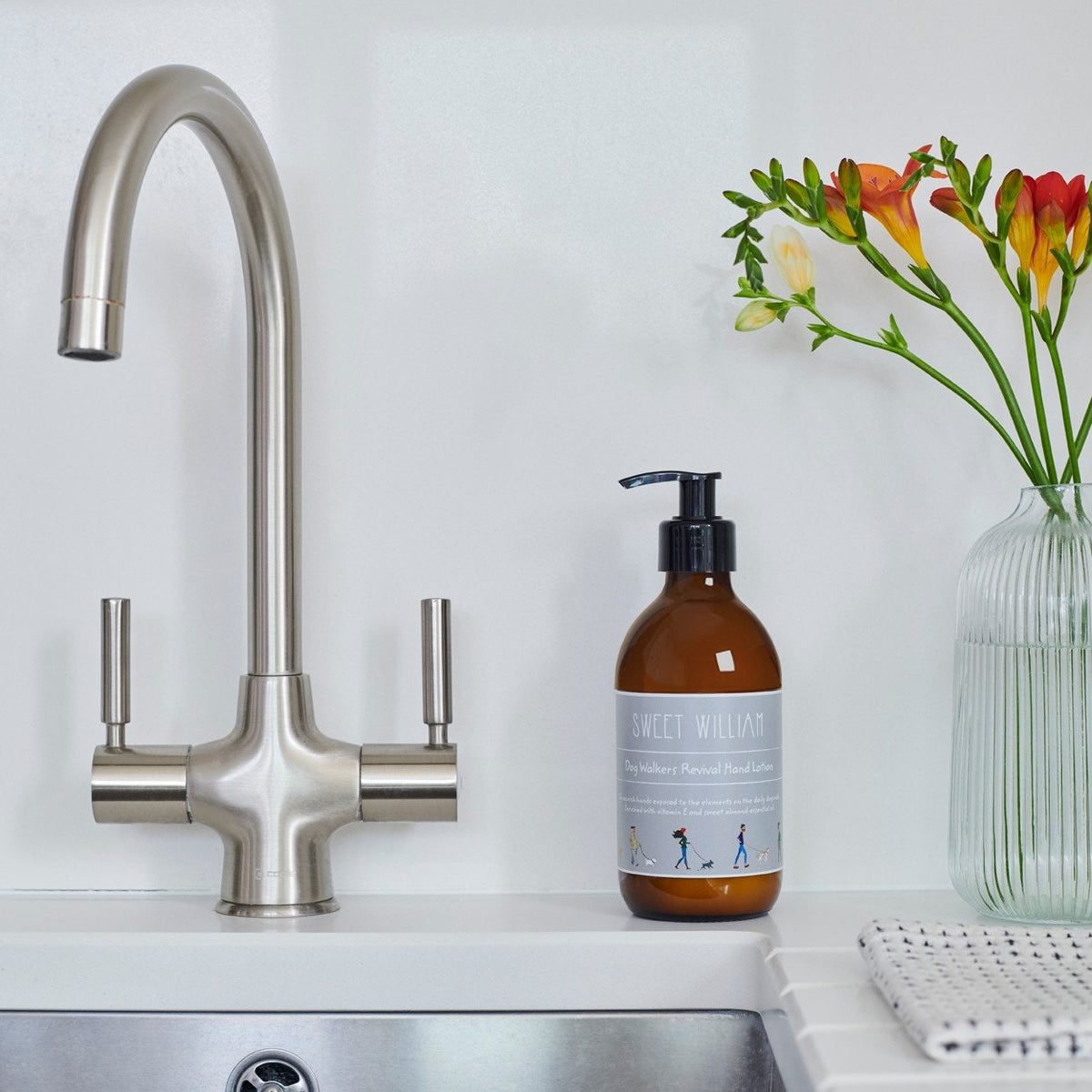 Dog Walkers Revival Hand Lotion on kitchen sink surface with flowers — natural hand lotion, thoughtful gift for dog walkers by Sweet William Designs