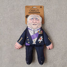 King Charles parody dog toy in navy ceremonial uniform with purple sash and medals — funny squeaky dog toy, royal family gift for dog lovers
