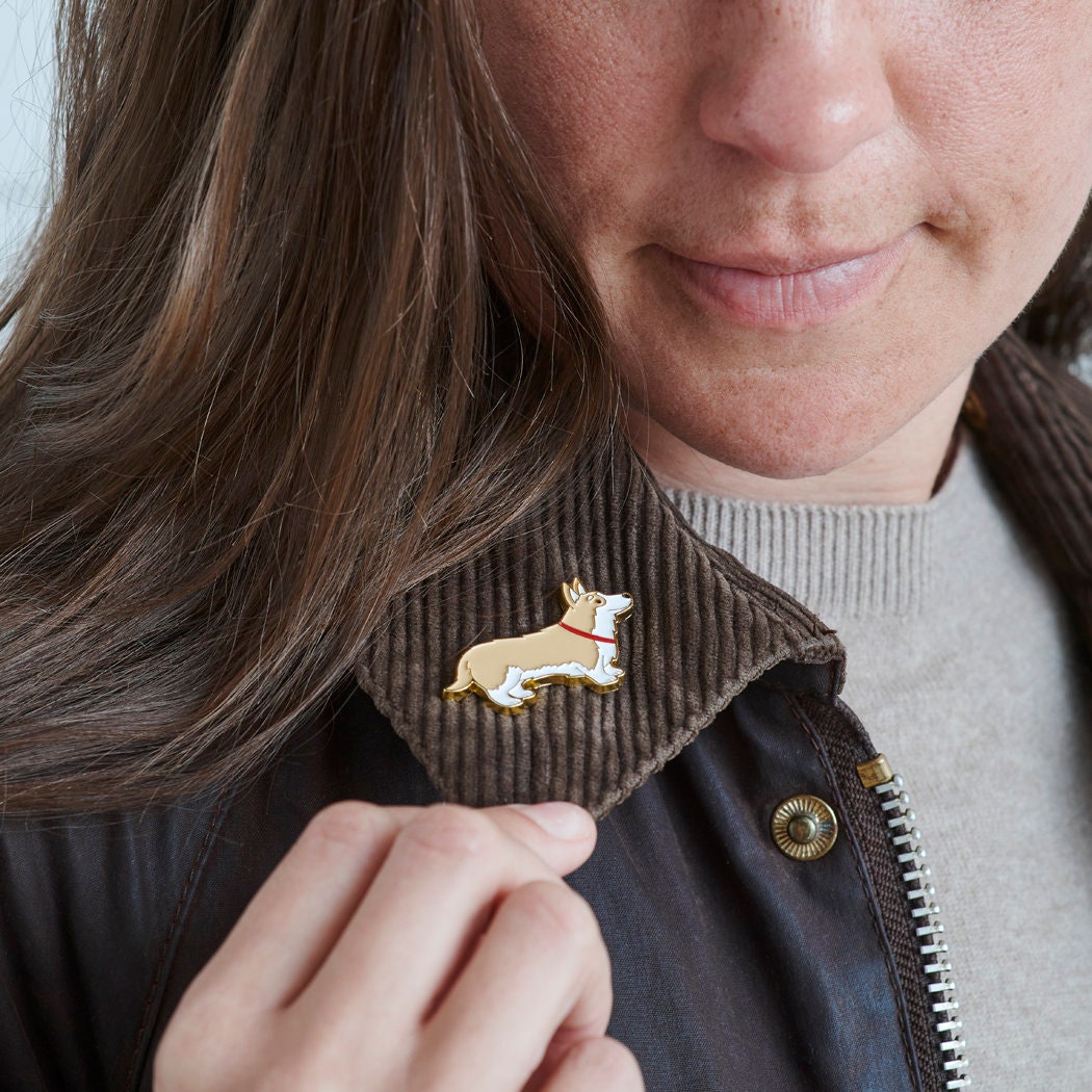 Close-up of Corgi enamel pin being attached to a corduroy jacket collar — gold-plated dog lover gift by Sweet William Designs