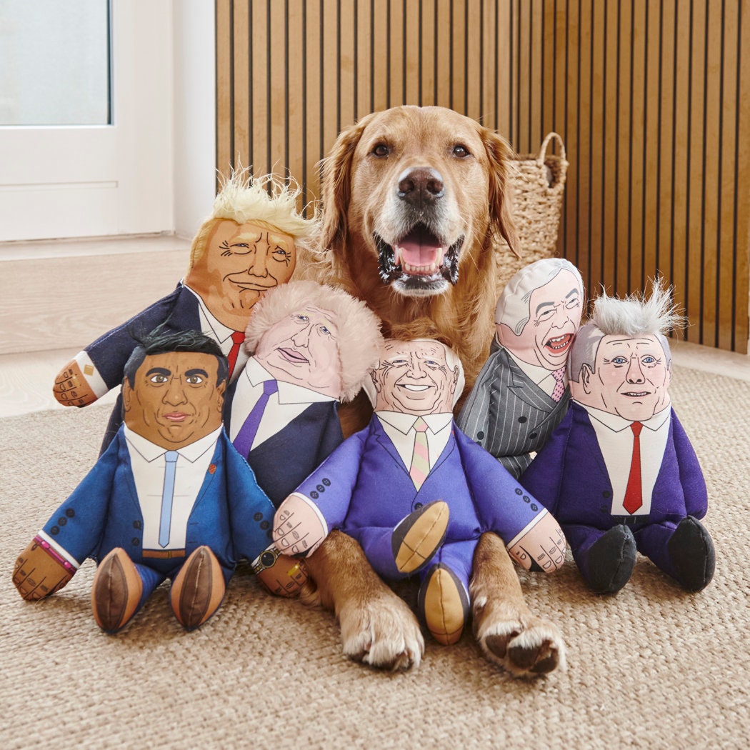 Golden Retriever surrounded by full range of political parody dog toys including Trump, Rishi, Boris and more — funny dog lover gifts