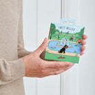 Black Schnauzer enamel dog pin held in hands on illustrated park backing card — gold-plated dog lover gift by Sweet William Designs