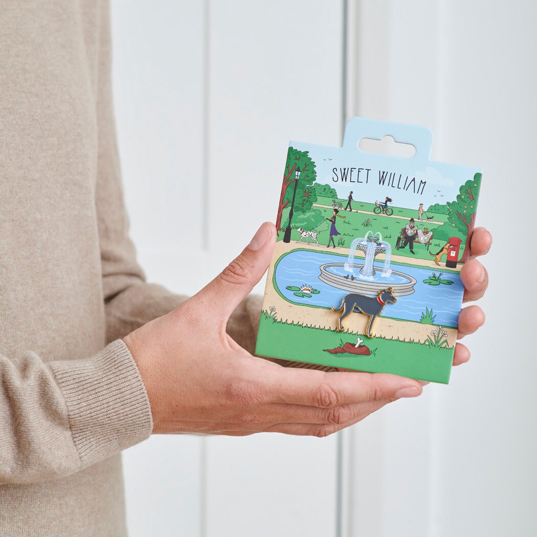 Lurcher enamel dog pin held in hands on illustrated park backing card — gold-plated dog lover gift by Sweet William Designs