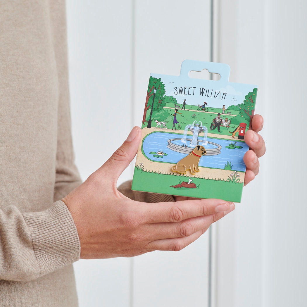 Pug enamel dog pin held in hands on illustrated park backing card — gold-plated dog lover gift by Sweet William Designs