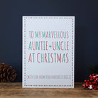 Auntie and Uncle Christmas card with red and green lettering, a star border and “With love from your favourite niece”, beside a pine cone and red berries.