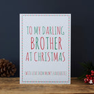 White Brother Christmas card with red and green lettering reading “To My Darling Brother at Christmas” and “With love from Mum’s favourite”, a star border, pine cone and red berries beside it.