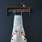 Jack Russell “The Great British Bark-Off” organic cotton apron hanging on wooden hooks, showcasing the full screen-printed design with two Jack Russell dogs, a fun gift for dog lovers