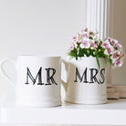 Ceramic Mr and Mrs mugs shown side by side with flowers, a lovely keepsake gift for a newly married couple