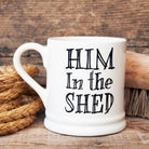 “Him in the Shed” ceramic mug, a funny gift for dads and grandads, styled with tools on a rustic wooden surface