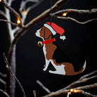 Beagle Christmas tree decoration hanging on lit winter tree — wooden dog decoration with Father Christmas hat and jingle bell collar by Sweet William Designs